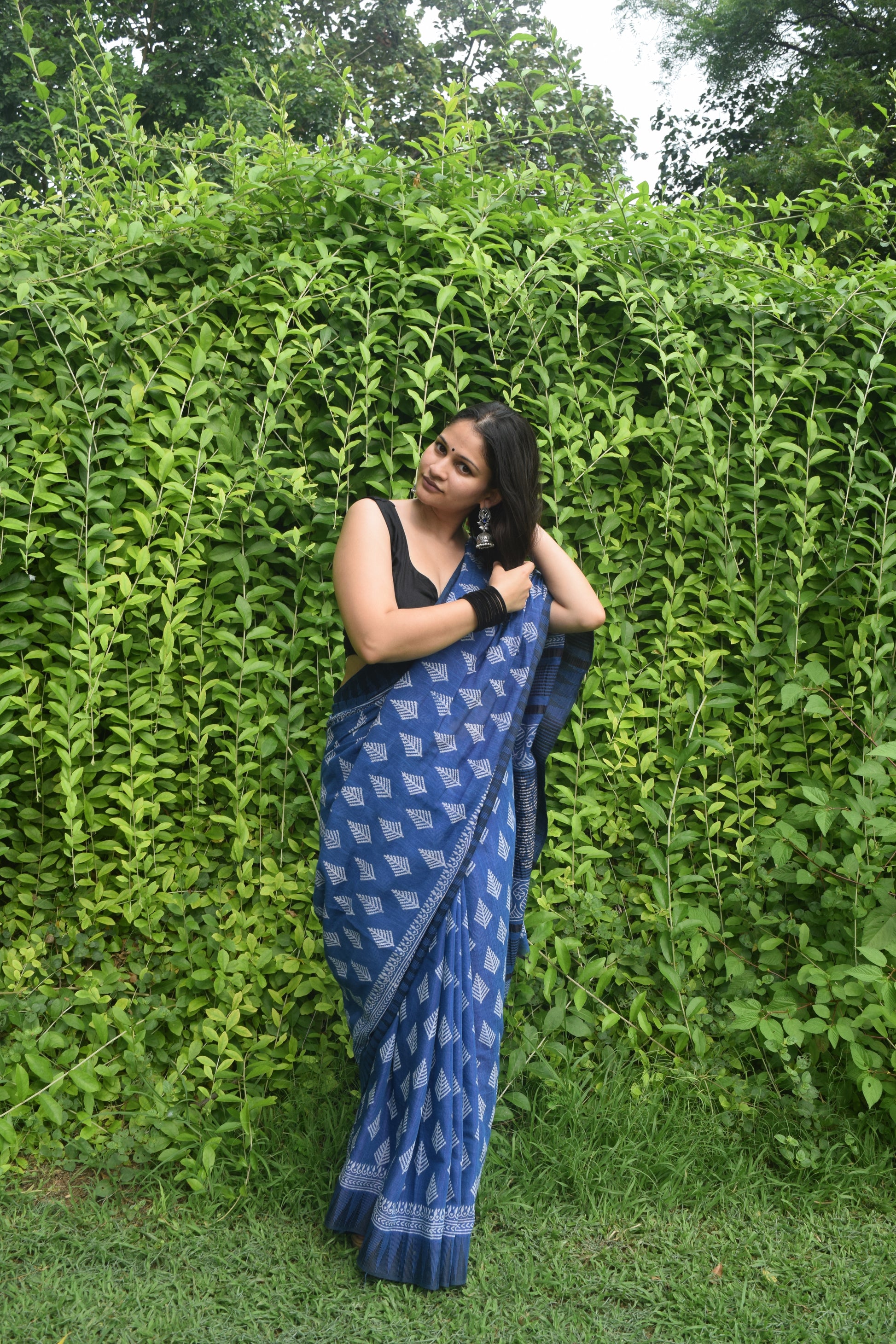 Woman in a blue saree lying on green grass