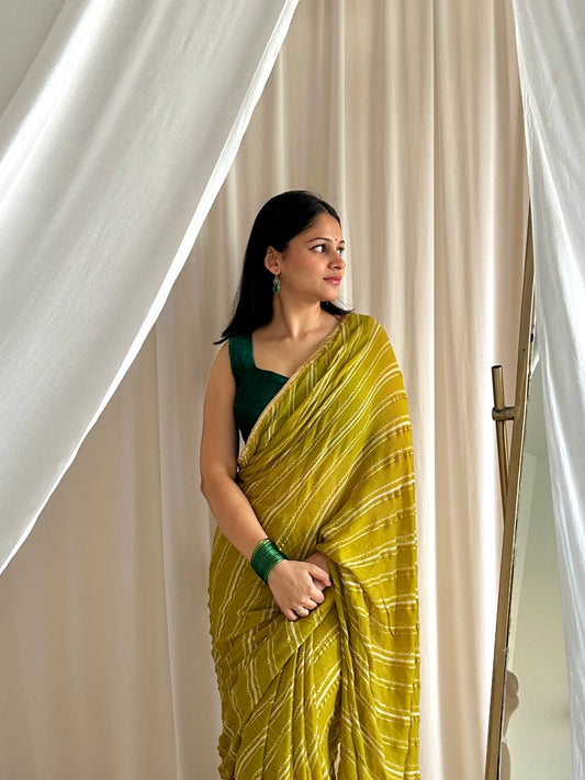 Woman wearing a green saree with a white curtain background