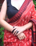 Person wearing a red and black patterned saree with a blurred background